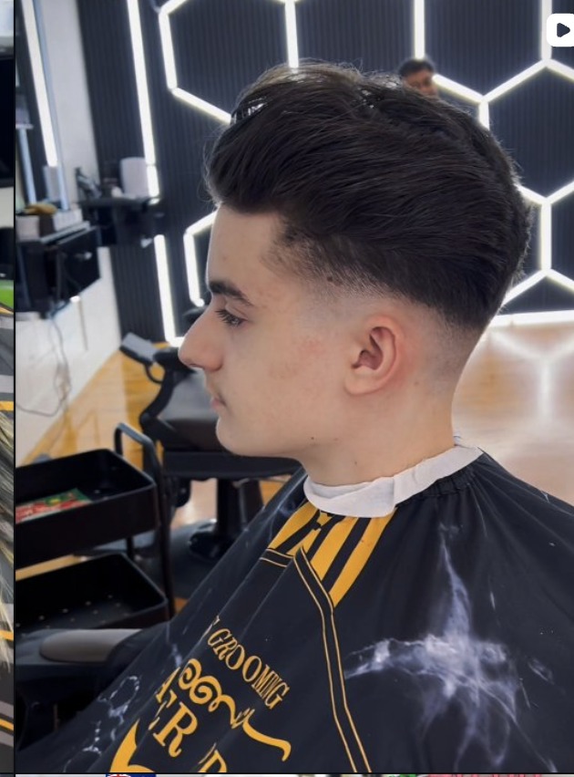 Sharp pompadour fade, cut in front of the glowing hexagon wall