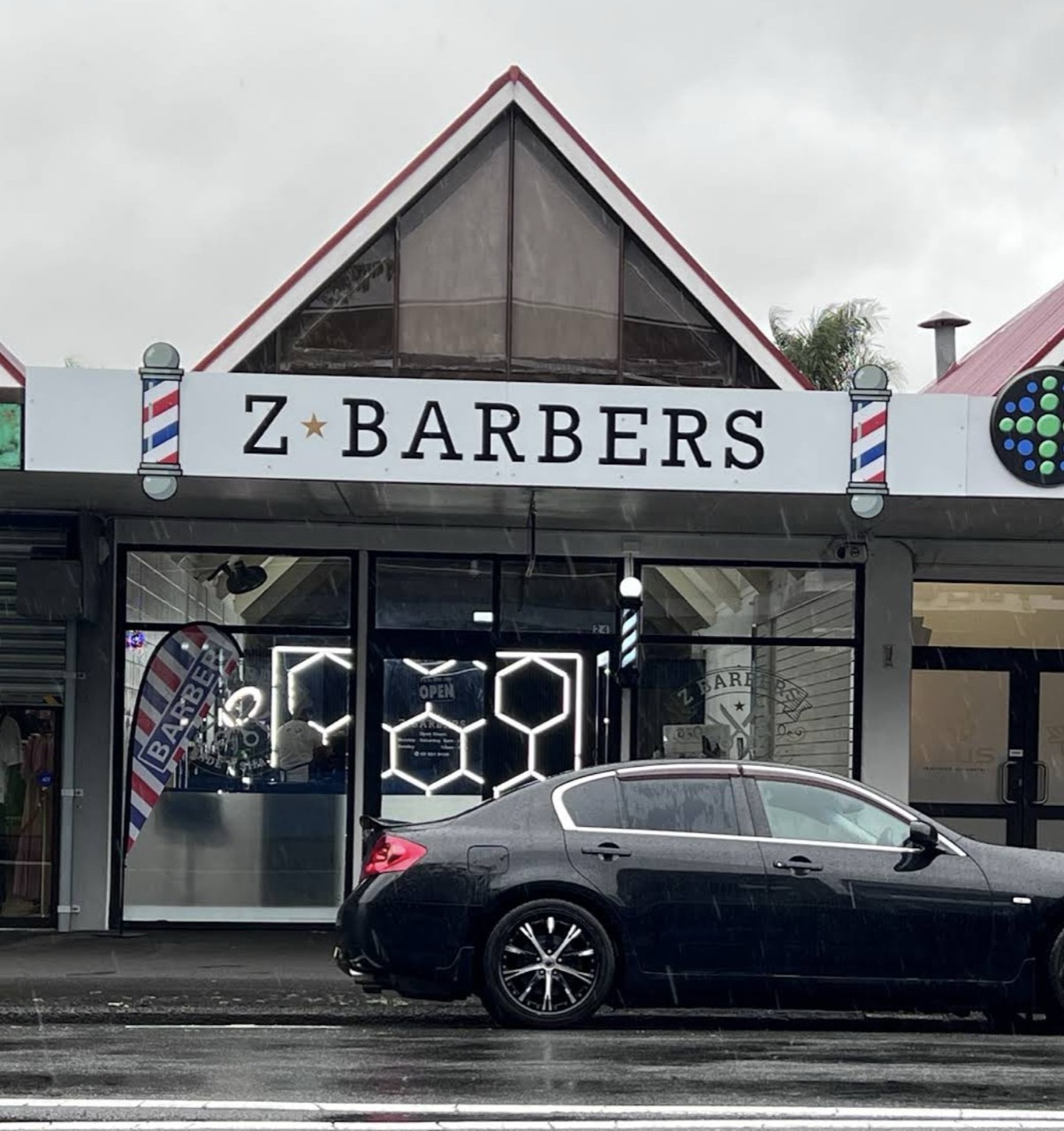 Z Barbers shopfront on John Street: white fascia, barber poles and red-framed doors under an A-frame gable